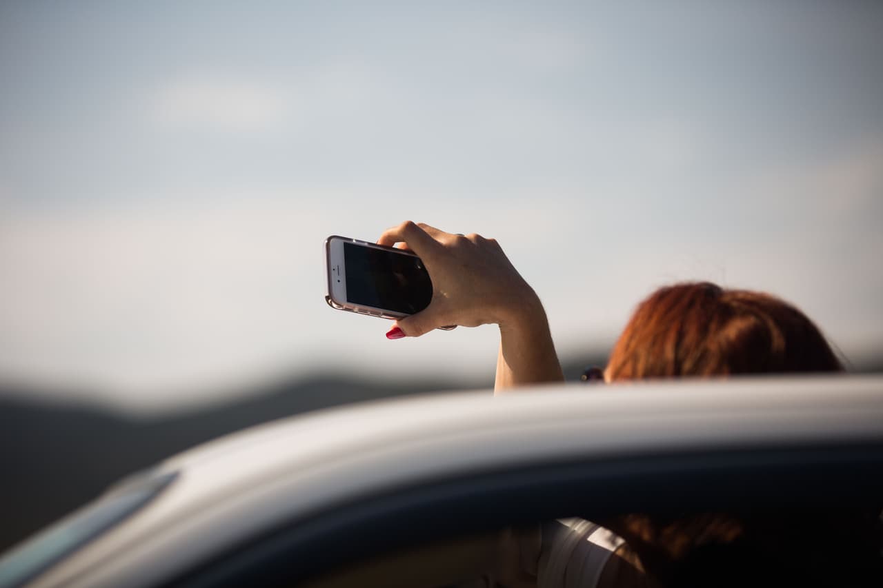 Una de las chicas en los carros de familiares y chambelanes graba video con su celular de la muchedumbre gritando y rodeando el carro donde viaja Rubí hacia la misa.