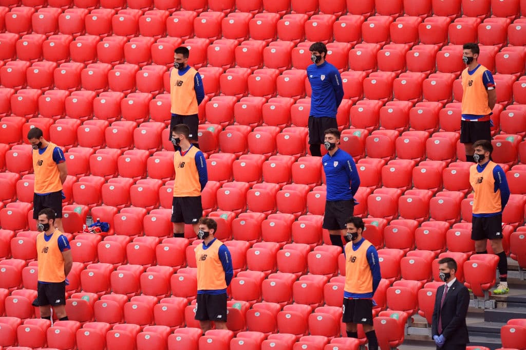 Los suplentes en las gradas también muestran su respeto por las víctimas del COVID-19.