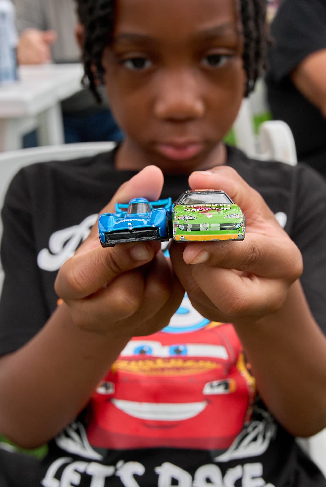 Jaxson Boyd, de 6 años y residente de Laurel, Maryland, sostiene los autos de juguete que llevó consigo a la zona de aficionados durante los eventos previos a la carrera de autos Freedom 250 Grand Prix.