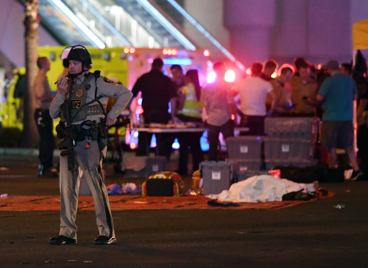 Un agente de la policía de Las Vegas habla por teléfono en el lugar de la masacre. Detrás de él yace el cuerpo de una de las víctimas cubierto por una manta de color blanco.