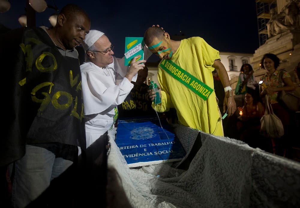Un hombre vestido como el papa Francisco utiliza una falsa constitución para bendecir a un manifestante durante una protesta en contra el juicio político de la presidenta de Brasil, Dilma Rousseff, en Río de Janeiro.
