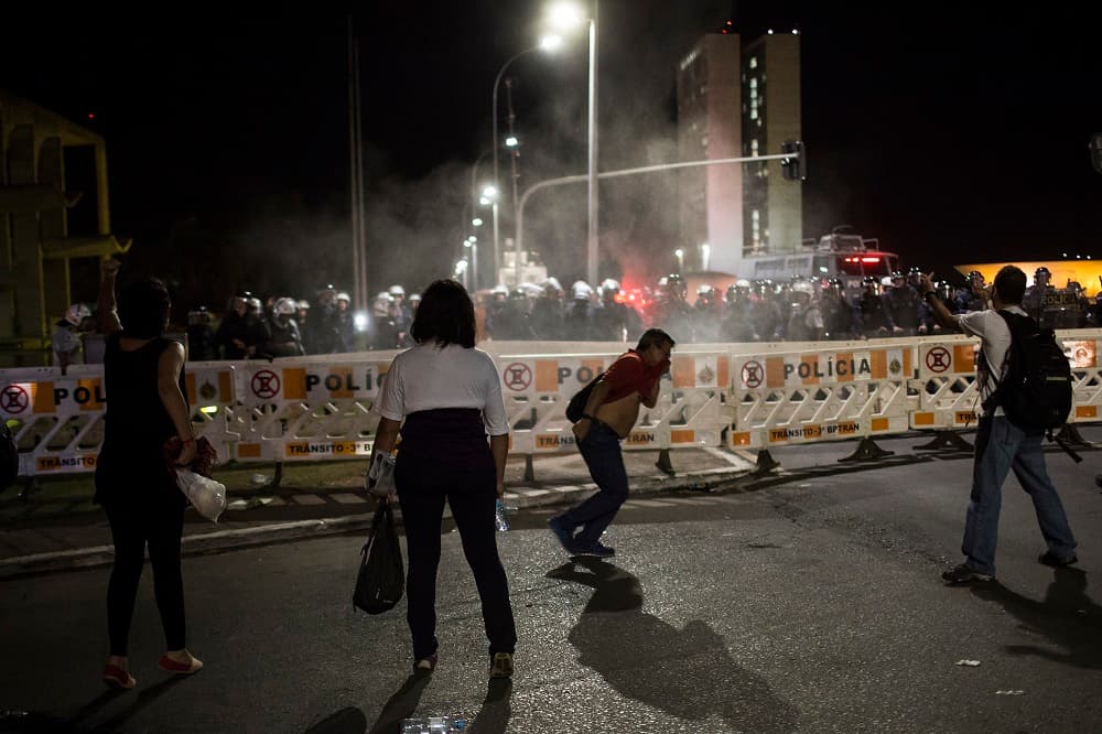 Manifestantes progubernamentales huyen de una nube de espray de pimienta durante enfrentamientos con la policía en el exterior del Congreso, en Brasilia.