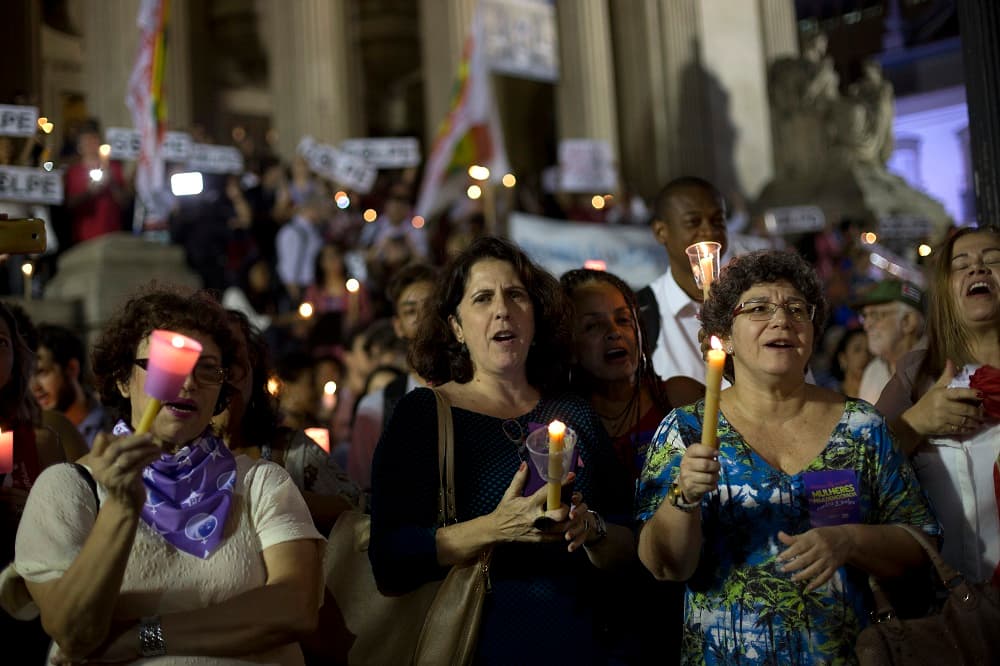 Manifestantes gritan lemas a favor del gobierno mientras sostiene velas durante una protesta en contra el juicio político de la presidenta de Brasil.