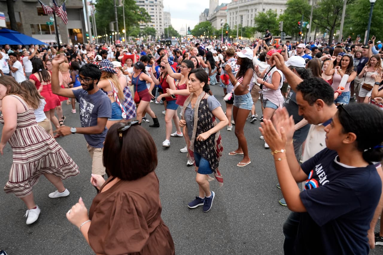 La gente baila en la calle mientras espera la reapertura del National Mall tras su evacuación debido al mal tiempo durante los actos del Día de la Independencia en conmemoración del 250 aniversario de la nación, el sábado 4 de julio de 2026, en Washington.