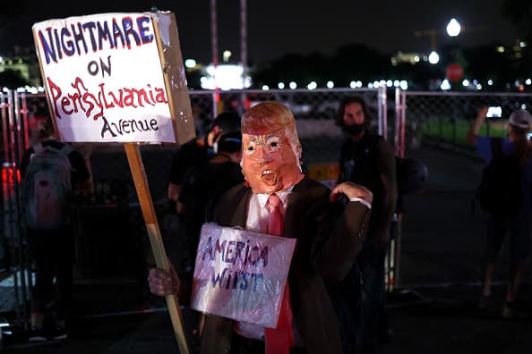 Un manifestantes protesta a las afueras de la Casa Blanca mientras el presidente acepta la nominación.