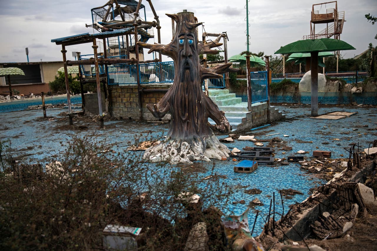En esta ciudad la rutina de algunos es revolver la basura, buscar comida y apresurarse a llenar cubos cuando el camión del agua llega al vecindario. En la fotografía la piscina en ruinas del parque 'Diversiones Grano de Oro', una feria temática abandonada en la ciudad.