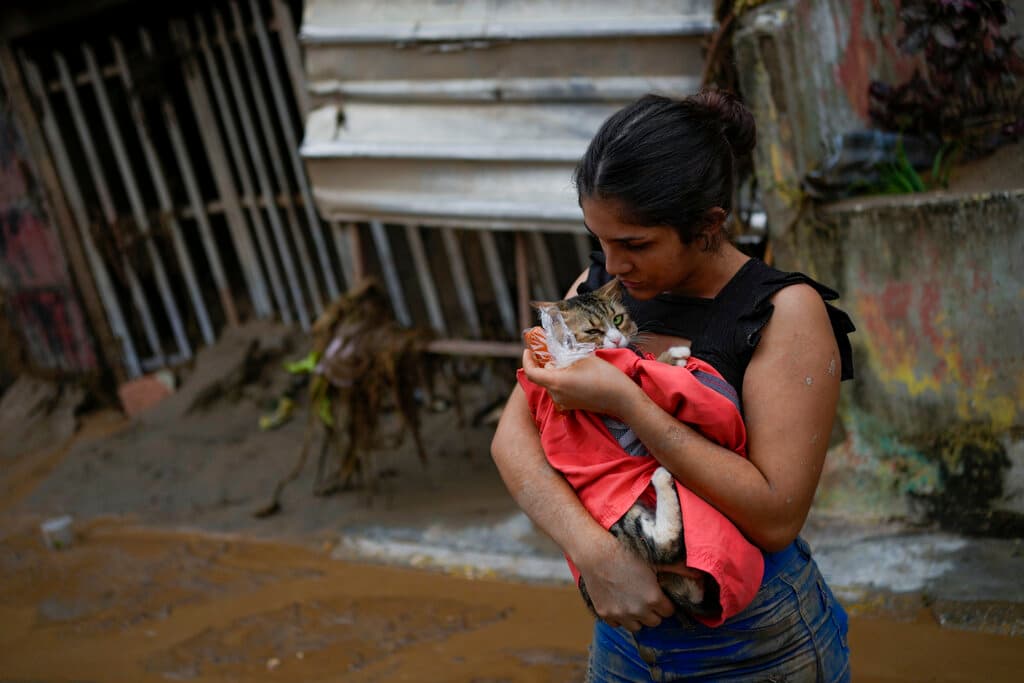Karen Salinas toma su gato entre sus brazos frente a su casa afectada por el deslave en Las Tejerías.