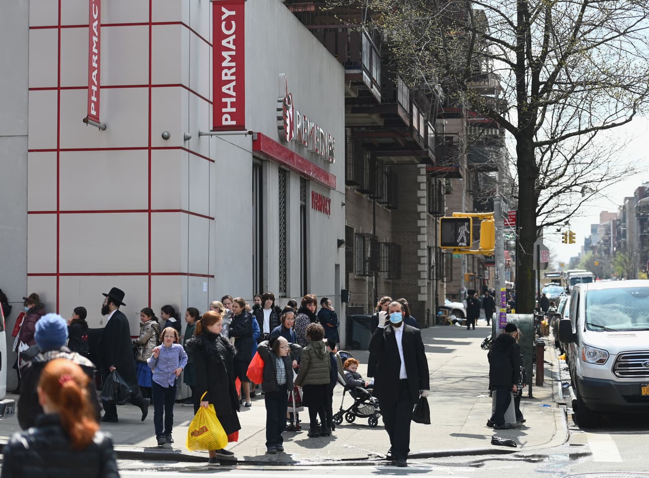 Miembros de la comunidad judía ortodoxa hacen cola en una farmacia.