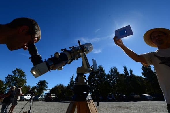 Mientras, Norm Vargas sostiene un filtro a través del cual se puede ver el eclipse sin dañar los ojos.