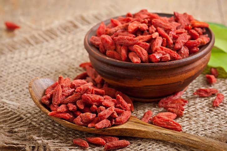 Red dried goji berries in wooden spoon