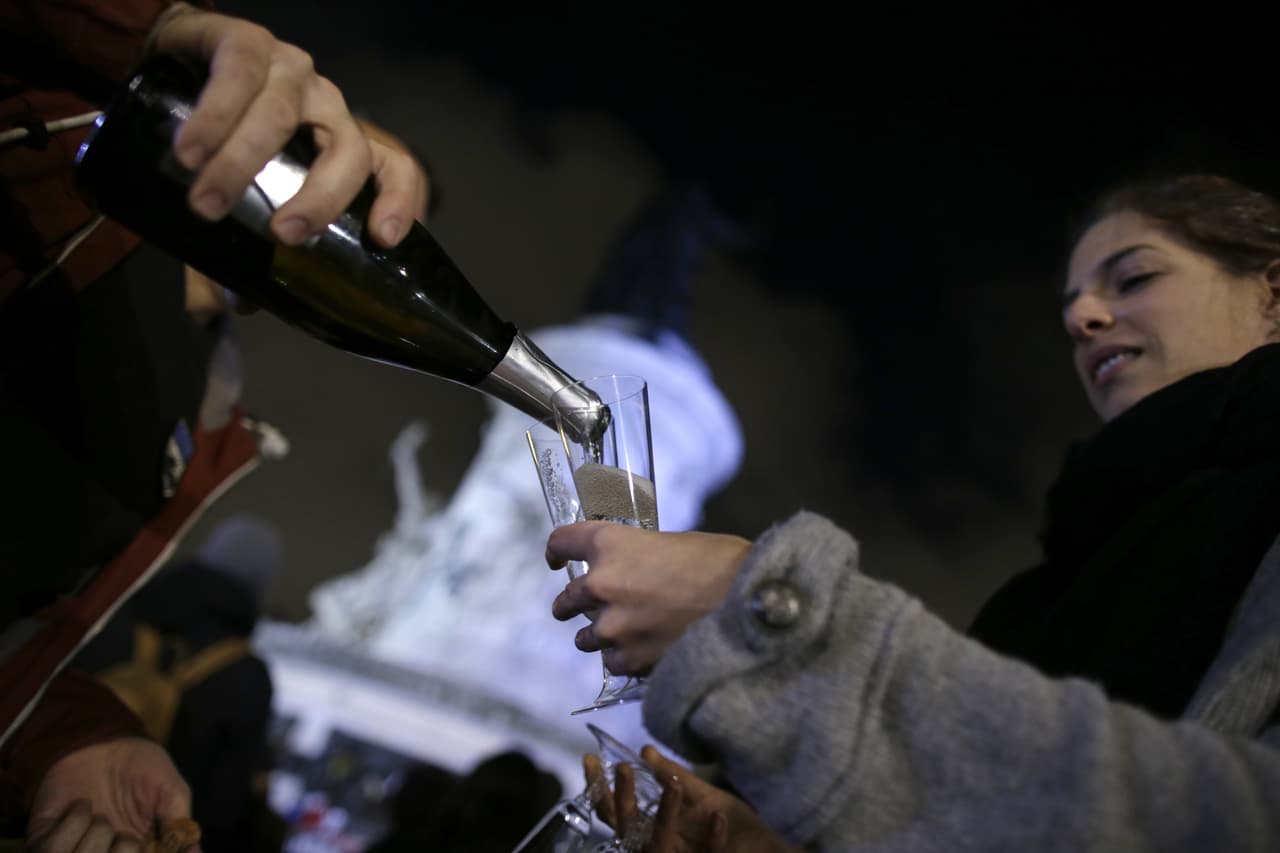 Un grupo de personas beben champagne durante un tributo cerca de un monumento en París.