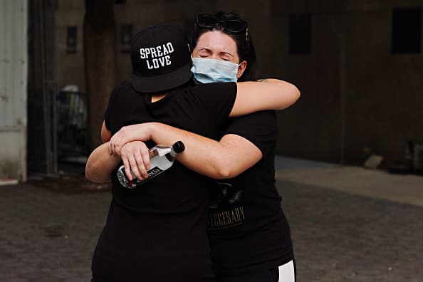 Si vas a abrazar a alguien que conoces, hazlo al aire libre, usa una máscara, los rostros deben apuntar en direcciones opuestas, hay que evitar el contacto entre tu cara y el cuerpo de la otra persona, sé breve y lávate las manos después. Esto limita el riesgo (pero no lo elimina).