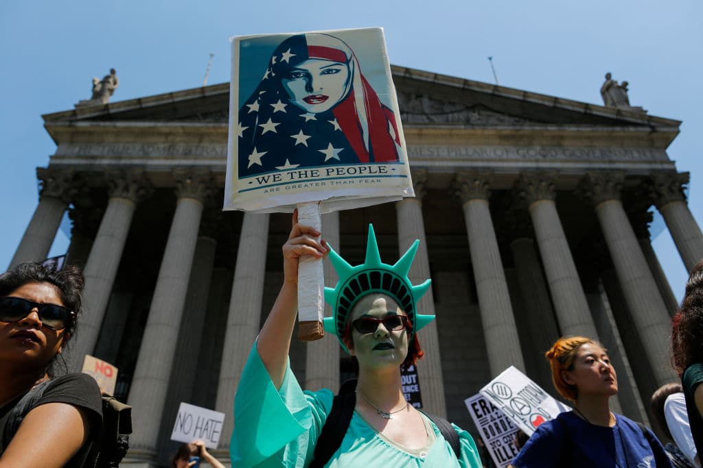 Una mujer disfrazada de estatua de la libertad en Foley Square de Nueva York sostiene un cartel alusivo a la defensa de las mujeres musulmanas.