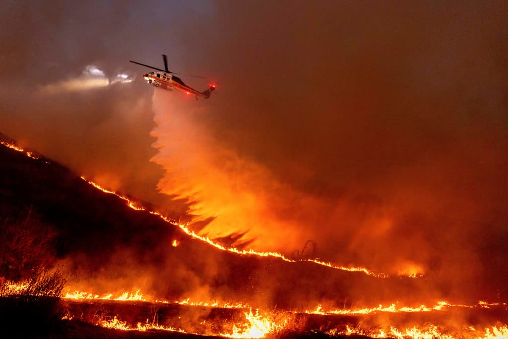 Un helicóptero arroja agua sobre las llamas en West Hills, Los Ángeles, el 9 de enero de 2025. (AP Foto/Ethan Swope)