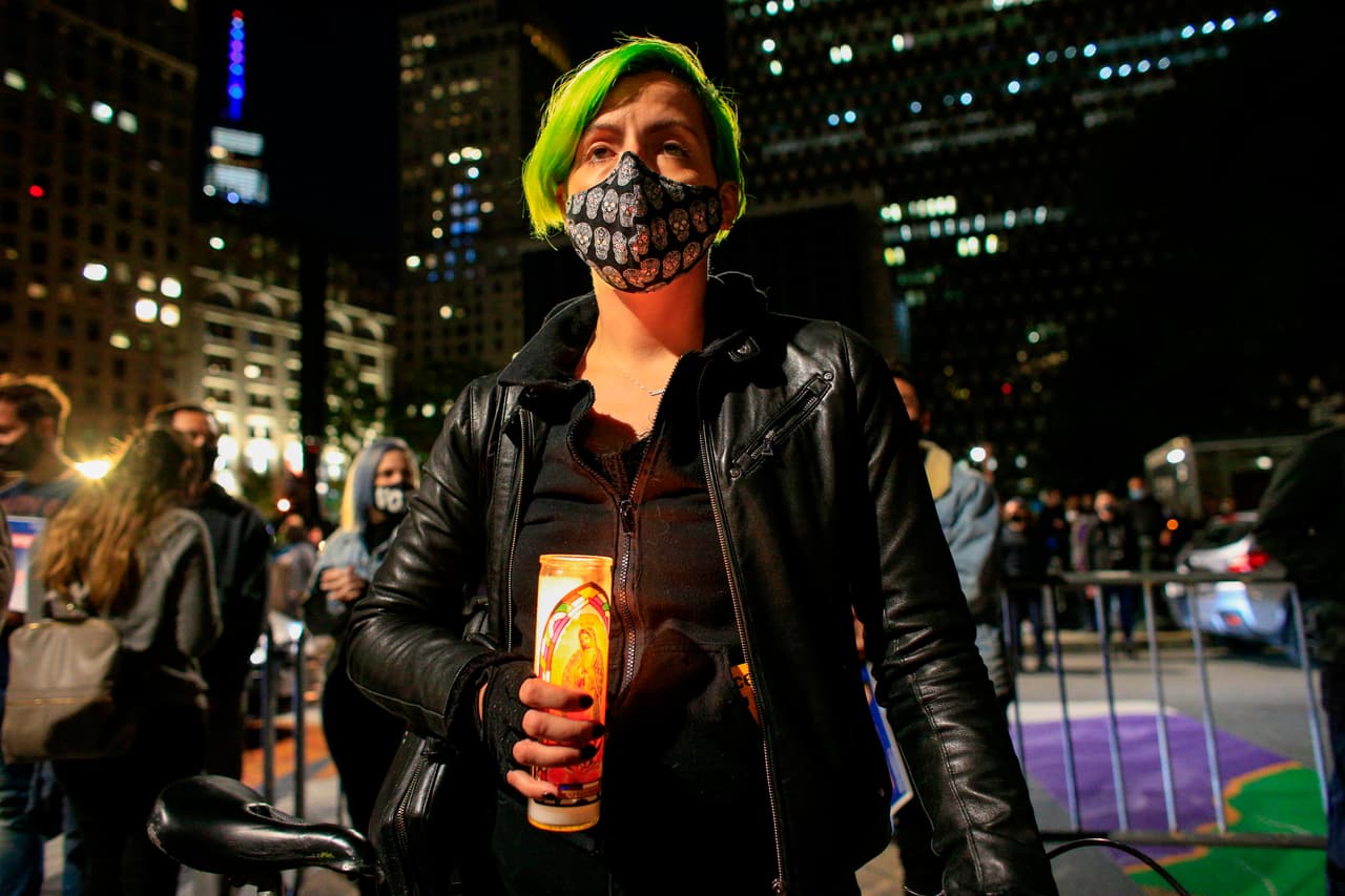 Una mujer sostiene una vela mientras la gente presenta sus respetos a RBG