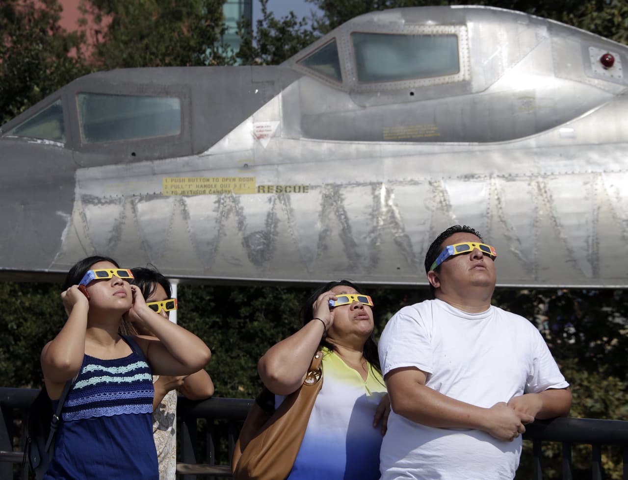 Un grupo de personas observa hacia el cielo durante el eclipse solar parcial en el Centro de Ciencias de California.
