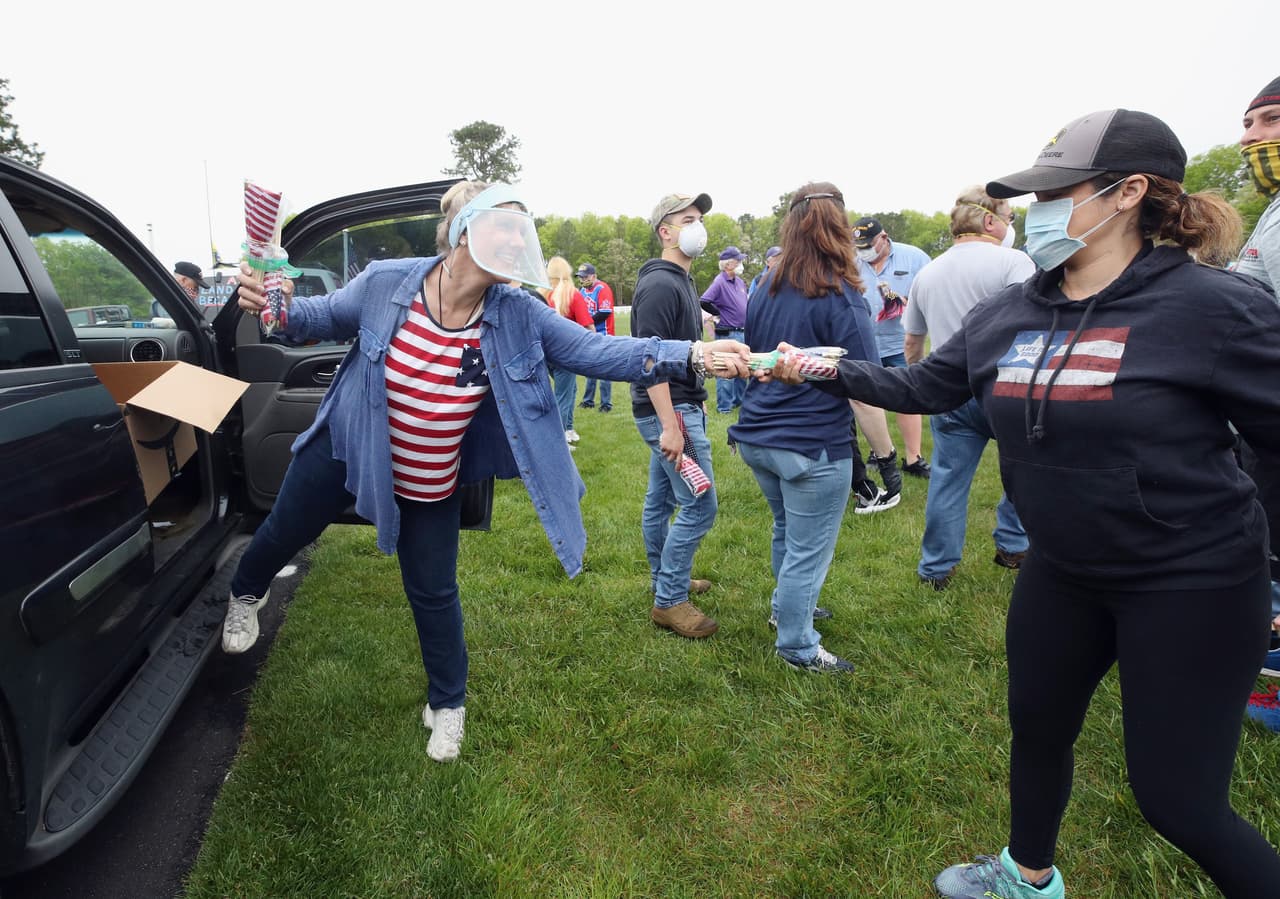 En medio de la pandemia de coronavirus, Holly Meyer entrega banderas a los voluntarios para colocarlas en las tumbas del Calverton National Cemetery el 23 de mayo en Wading River, Nueva York.