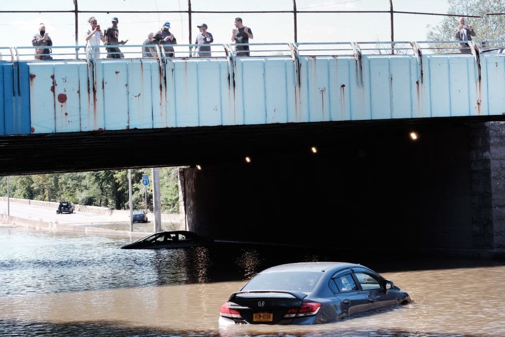 Pobladores del Bronx, Nueva York, miran los autos abandonados en la autopista Major Deegan Expressway inundada después de una noche de lluvia extremadamente fuerte.