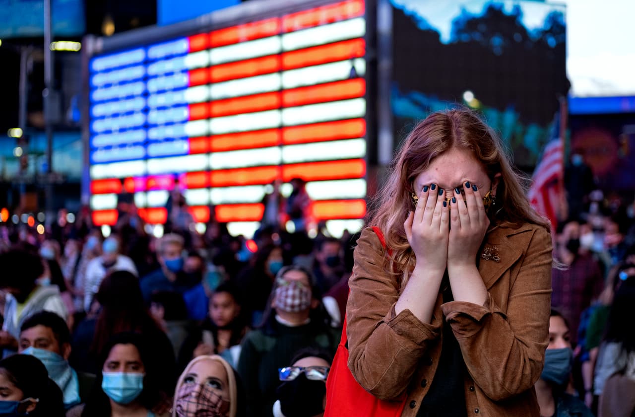 Manifestantes emocionados miran el discurso de Joe Biden en Times Square, Nueva York.