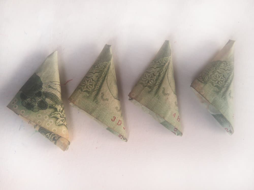 Hacer con el billete un triángulo y ponerlo entre las manzanas y la veladora.