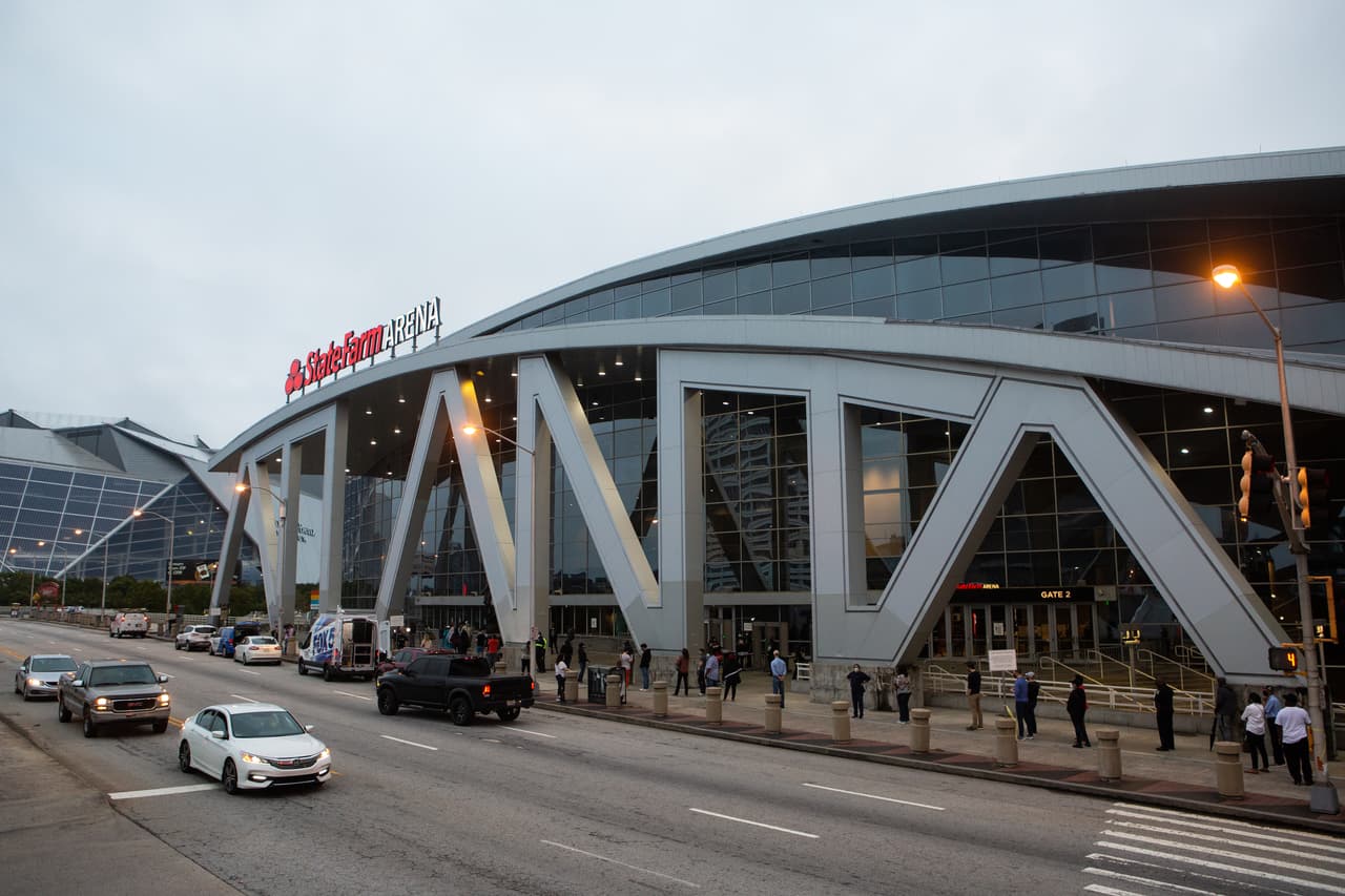 Los votantes esperan a las afueras del State Farm Arena para emitir sus votos en el primer día de votación anticipada en Georgia.