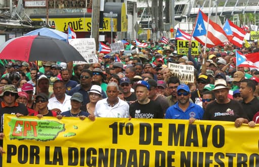 Un grupo de manifestantes camina en el área metropolitana hacia la zona donde están ubicadas las sedes de los principales bancos que operan en la isla. (AP)
