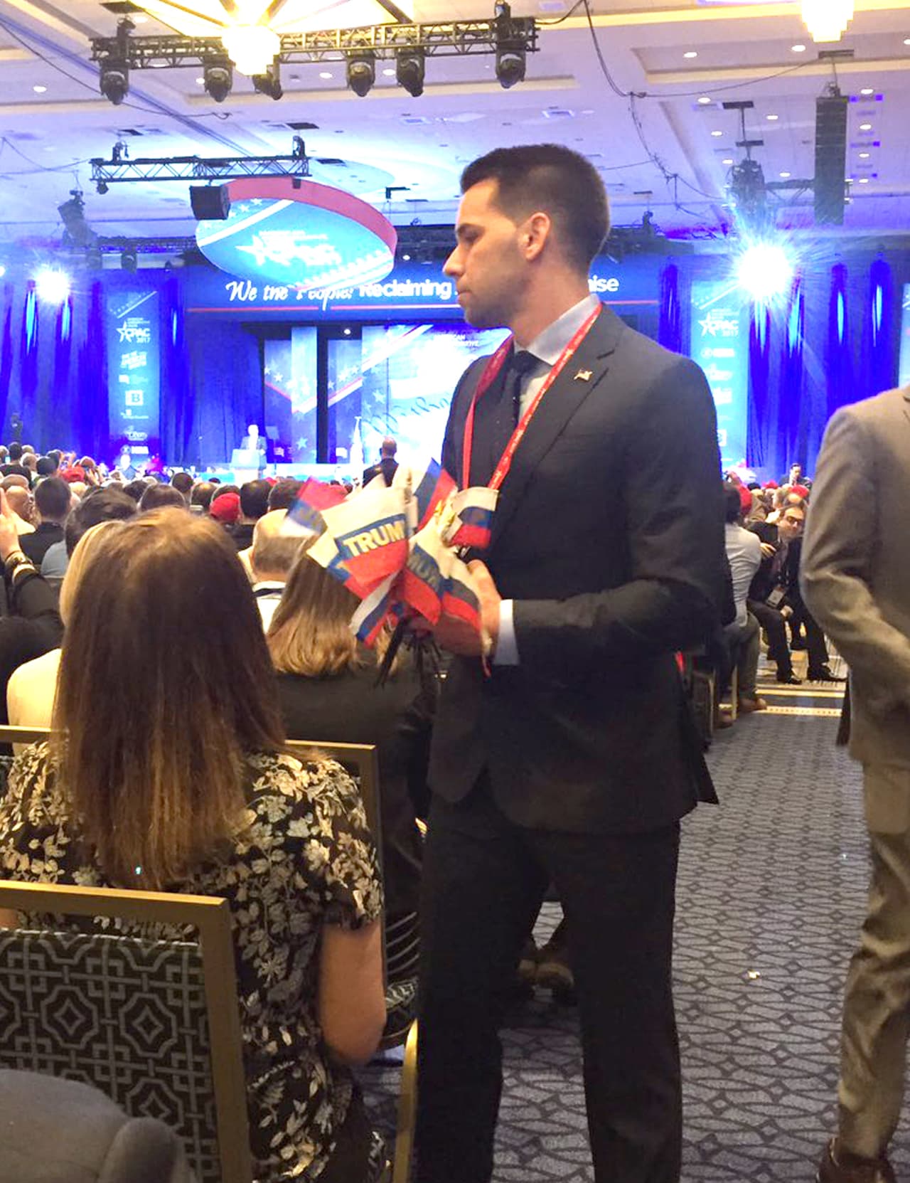 Momento en que fueron retiradas las banderas por el personal de la Conferencia, durante la presentación de Donald Trump en el evento.