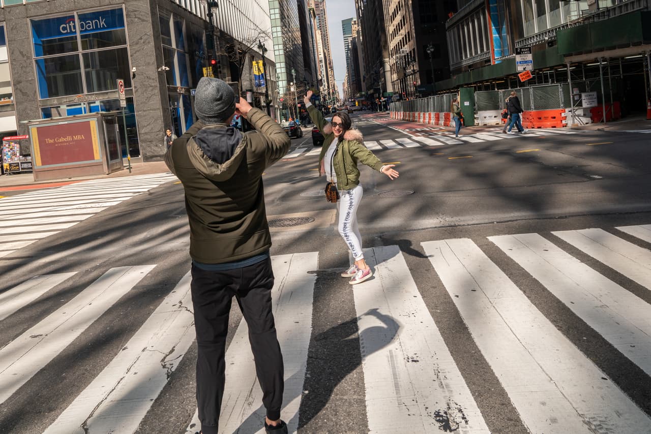 Una turista se toma una foto en la intersección de la calle 42 y la Avenida Madison en Manhattan, sorprendentemente vacía.