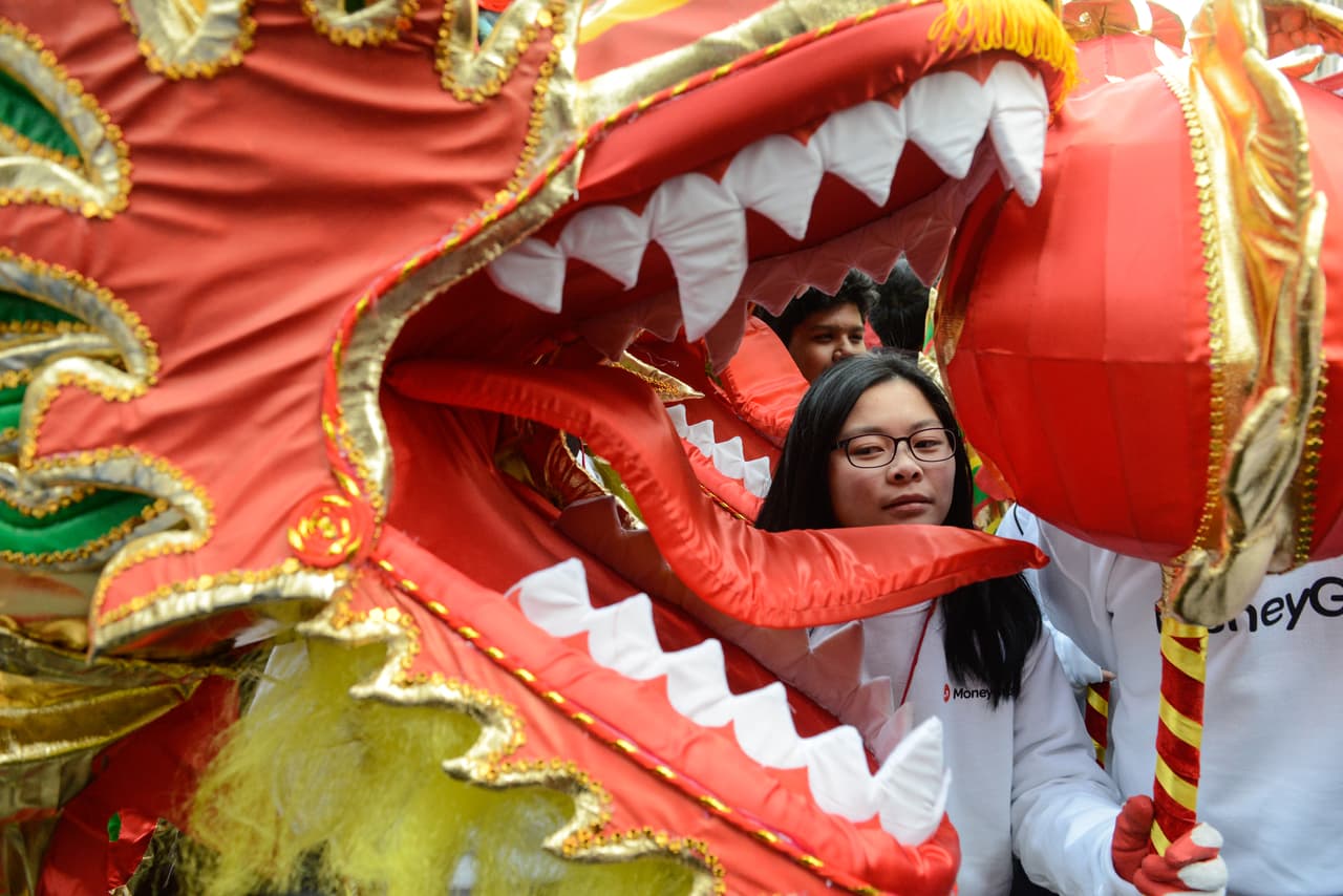 Una mujer posa frente al rostro de un dragón durante las celebraciones en NY.
