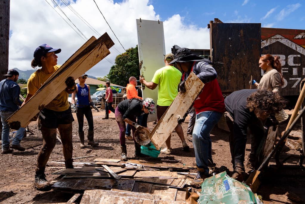 Unos voluntarios cargan escombros y enseres domésticos dañados en un camión durante las labores de limpieza tras las inundaciones, el martes 24 de marzo de 2026, en Waialua, Hawaii.