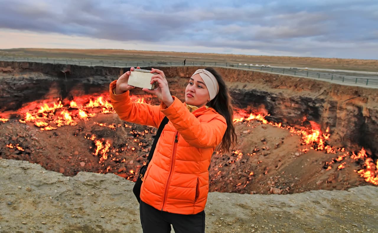 <b>Un gran agujero.</b> El suelo colapsó y se tragó al equipo dentro del inmenso hoyo. El evento provocó que la roca sedimentaria del desierto también colapsara en otros lugares cercanos, un efecto dominó que dejó varios cráteres pequeños abiertos. En la fotografía, una chica se toma una fotografía frente a la ‘puerta del infierno’ en marzo de 2019.