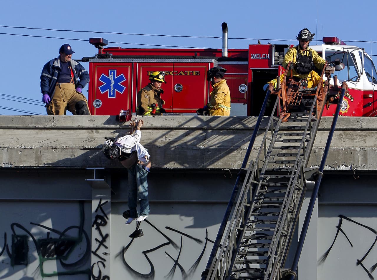 Bomberos retiran el cadáver de un hombre colgado en un puente.