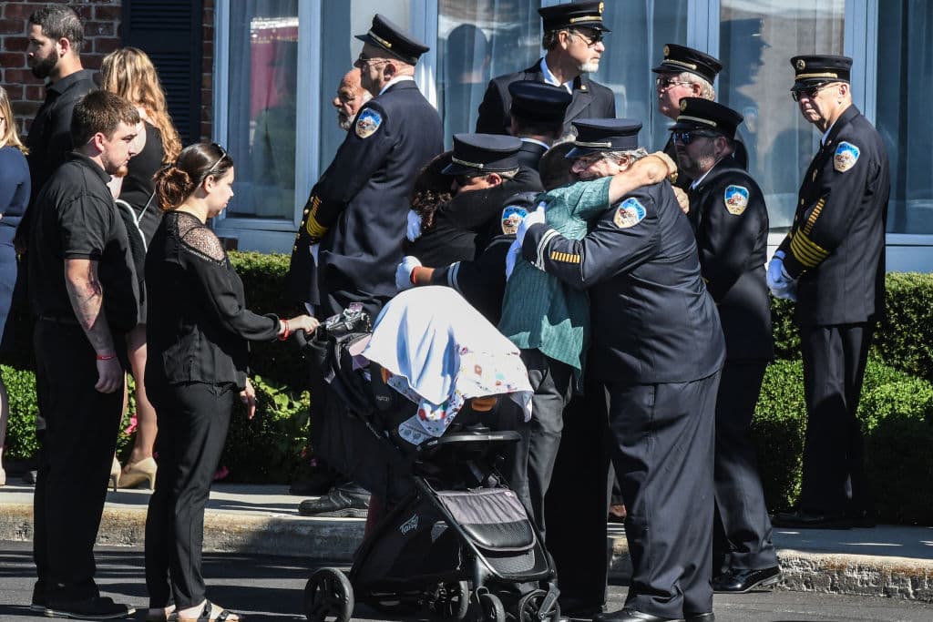 Miembros del cuerpo de bomberos y sus familias se abrazan con pena ante la tragedia ocurrida, que ha tenido un gran impacto en todo el país.