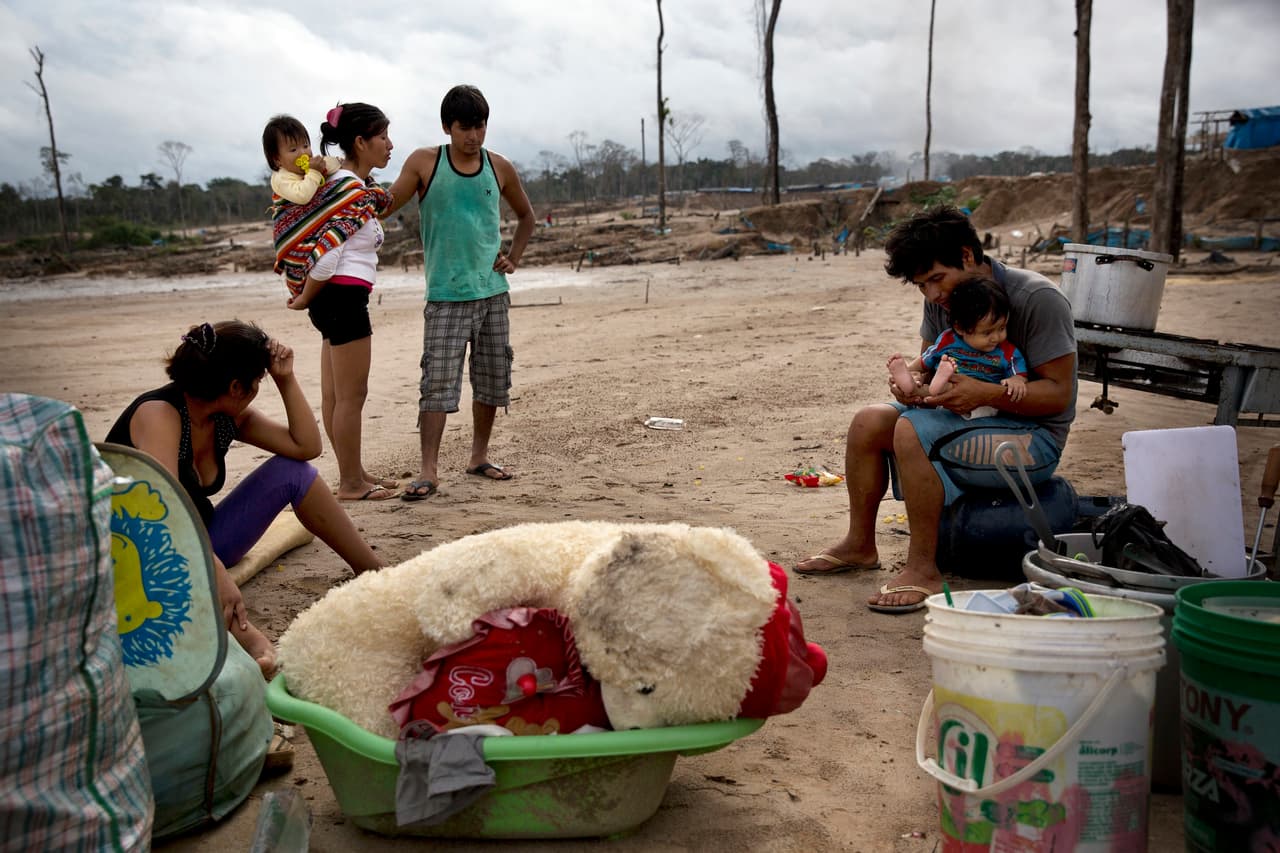 Una familia de mineros informales rodeados de algunas de sus pertenencias tras ser desalojados.