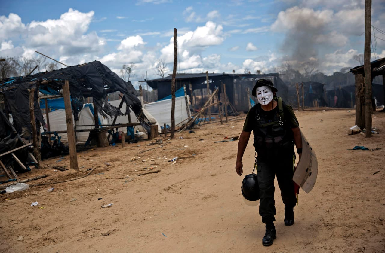 Un hombre, con el rostro pintado, camina sobre el campo que fue allanado por la policía. La mayoría de los mineros son campesinos.
