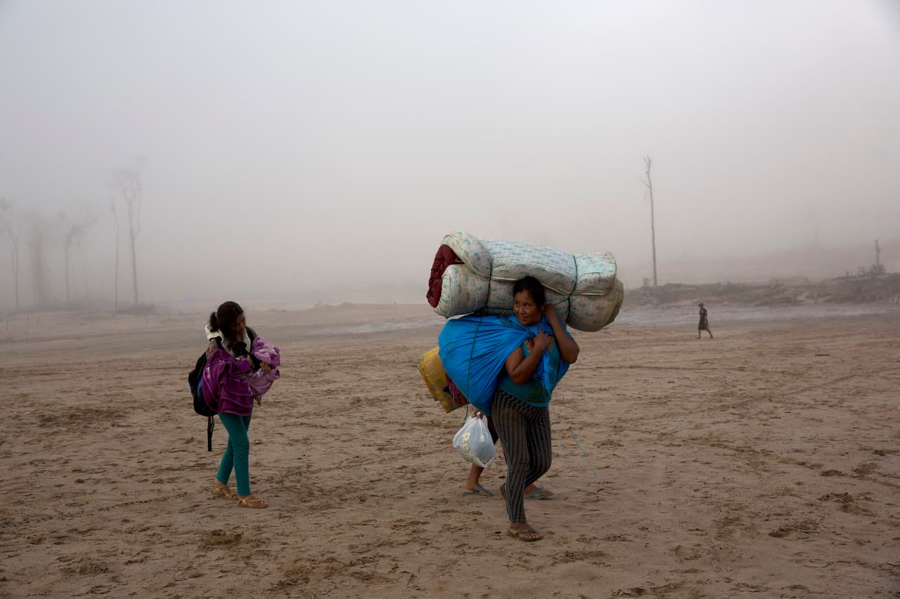 Las decenas de habitantes de estos campamentos fueron sorprendidos cuando llegaron los operativos policiales. Una mujer y un niño cargan algunas de sus pertenencias tras ser desalojados.