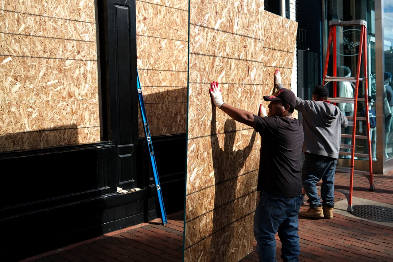 Trabajadores cubren con tablas de madera, los vidrios de una tienda cerca de la Casa Blanca en esta jornada electoral.