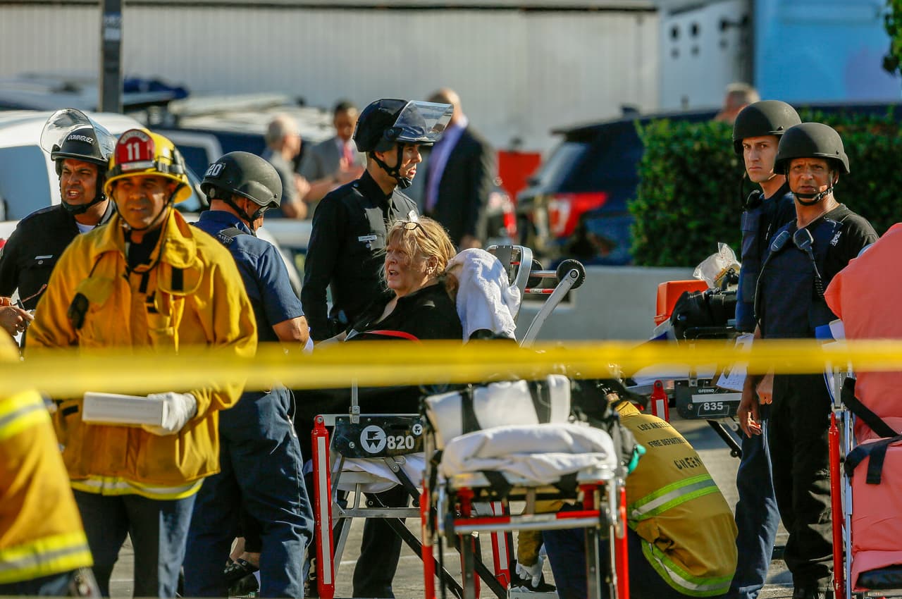 Una mujer no identificada que resultó herida por el pistolero es ayudada por paramédicos para ser llevada a un hospital.