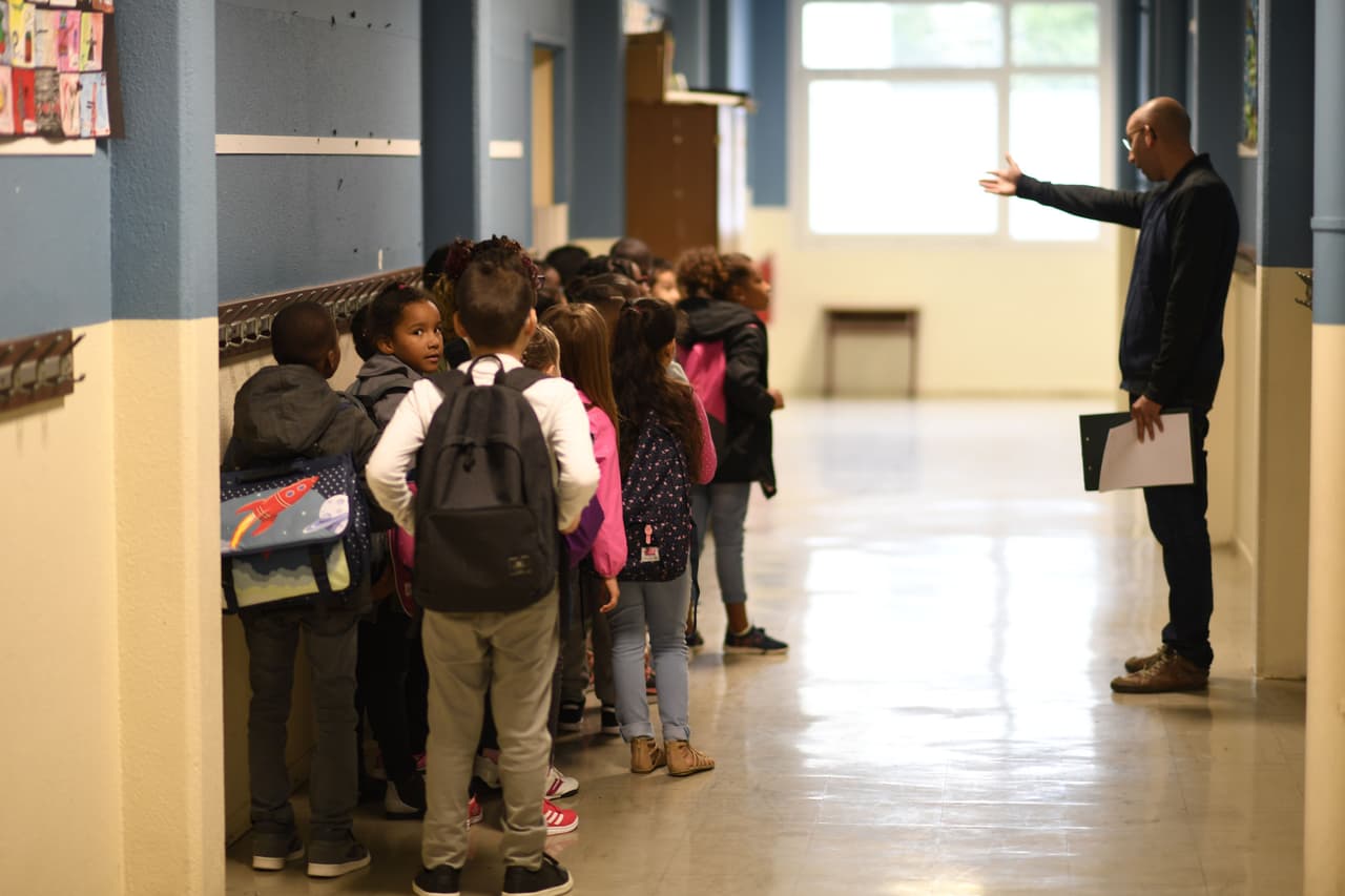A teacher speaks to his pupils in a corridor prior to enter in a classroom at a primary school at the start of the new school year on September 4, 2017, in Corbeil-Essonnes, outside Paris. / AFP PHOTO / CHRISTOPHE SIMON (Photo credit should read CHRISTOPHE SIMON/AFP/Getty Images)