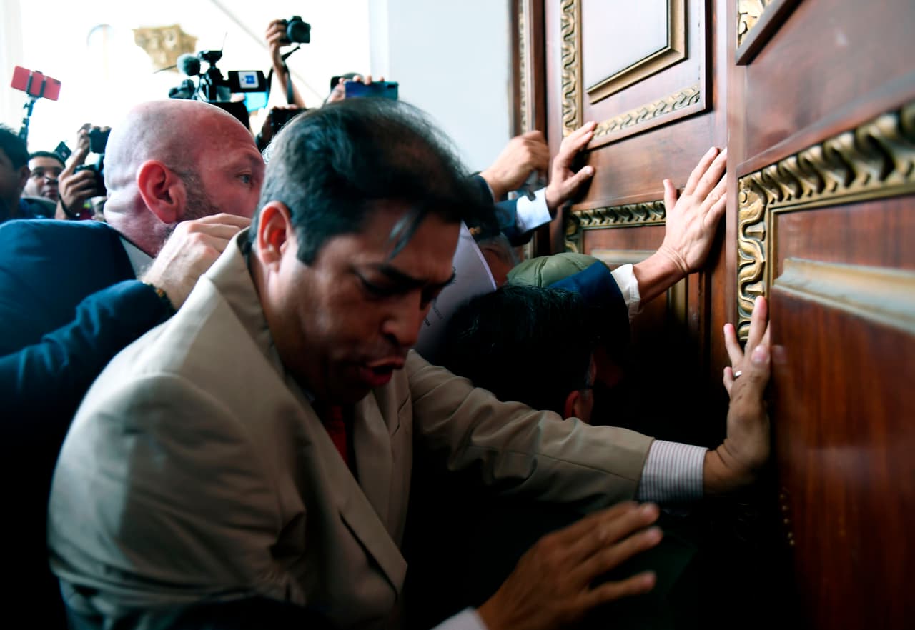 Diputados opositores al gobierno de Nicolás Maduro empujan la puerta del parlamento, bloqueada por funcionarios de la Guardia Nacional Bolivariana. Liderados por Juan Guaidó, varias decenas de diputados lograron el martes ingresar al palacio legislativo y recuperar el control de la Asamblea Nacional.