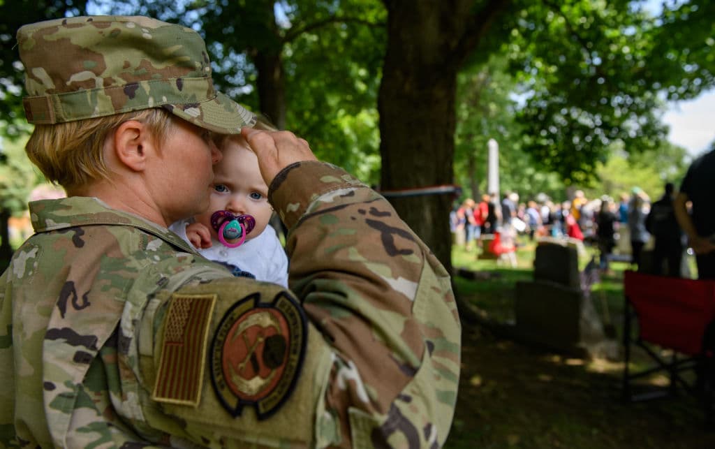 Rebecca Harsh, de 40 años y veterana de 16 años de la Fuerza Aérea saluda con su hija de 11 meses, Finley, durante la reproducción de Taps en el cementerio Oakmont-Verona durante un memorial servicio en el Desfile del Día Conmemorativo Oakmont-Verona el lunes 31 de mayo de 2021 en Oakmont, Pensilvania.