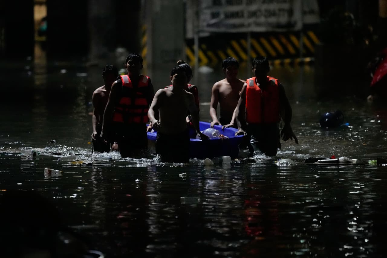 Unos hombres empujan una pequeña barca para ayudar a los residentes a transitar por una calle inundada a causa de las intensas lluvias monzónicas en la ciudad de Quezon, Metro Manila, Filipinas, el lunes 17 de agosto de 2026.