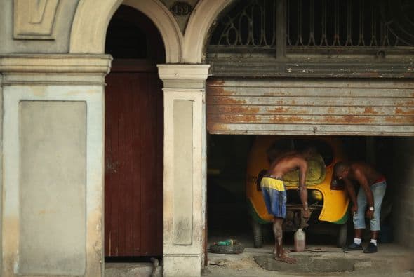 Mecánicos trabajan en un garaje para reparar el motor de un Taxi.