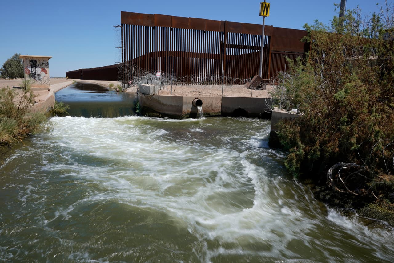 El agua del río Colorado fluye por un canal junto al muro que separa San Luis Río Colorado, México, de San Luis, Arizona, el 14 de agosto del 2022. Cada vez llega menos agua del río Colorado a México.