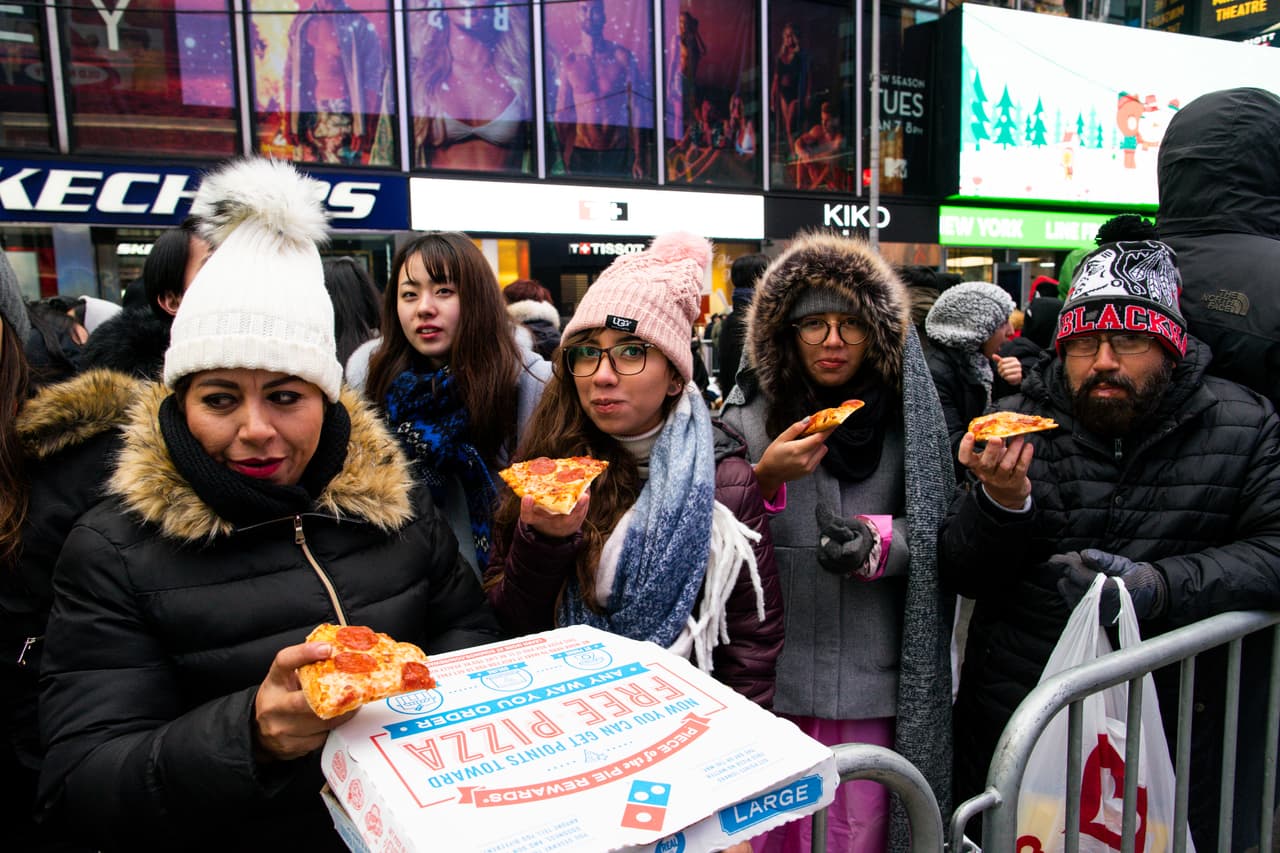 Algunos asistentes comen pizza mientras esperan para recibir el Año Nuevo en Times Square.