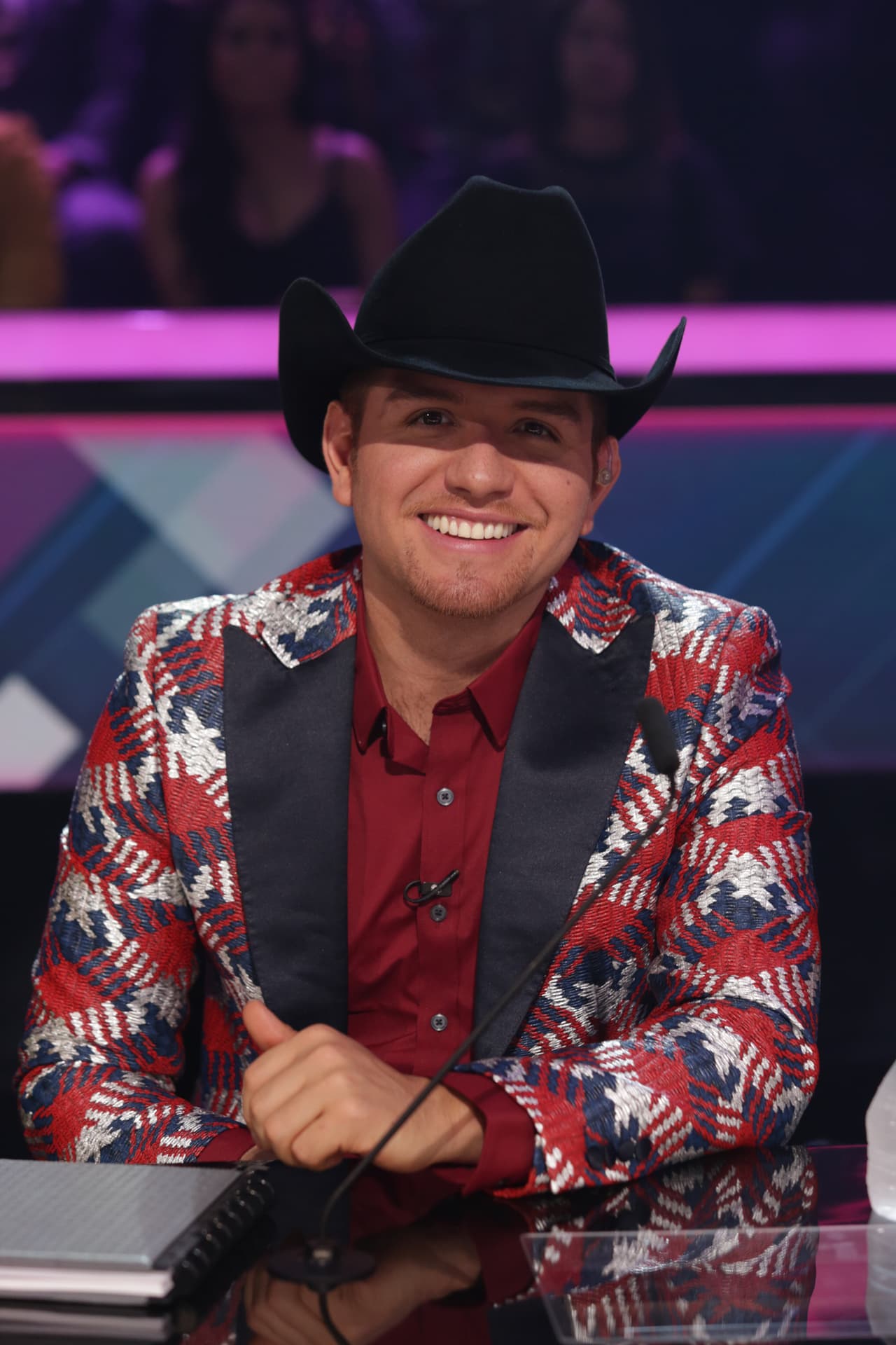 El cantante de música regional mexicana llega a cada gala de Nuestra Belleza Latina con su cabeza cubierta y sus vistosos trajes.