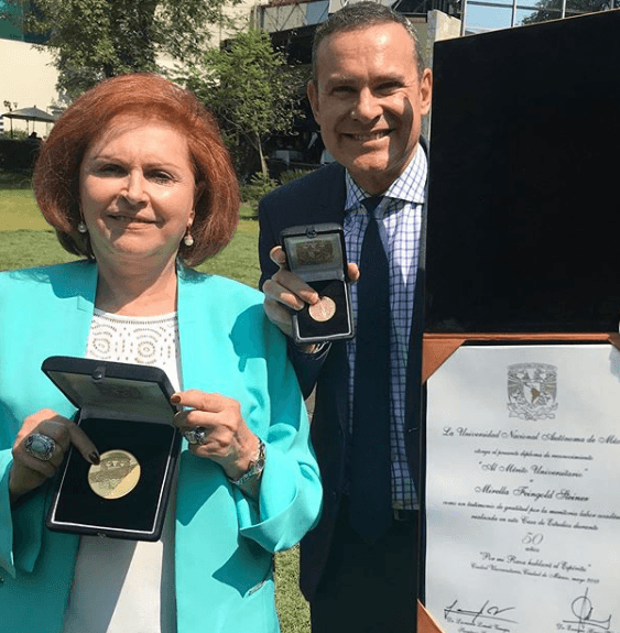 En una ceremonia organizada por la Universidad Nacional Autónoma de México, la doctora Mirella Feingold, madre de Alan, recibió el reconocimiento al mérito universitario por 50 años como maestra en la máxima casa de estudios de México.