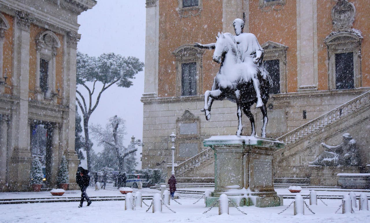 Algunos transeúntes en la plaza del Capitolio bajo la inusual nevada.