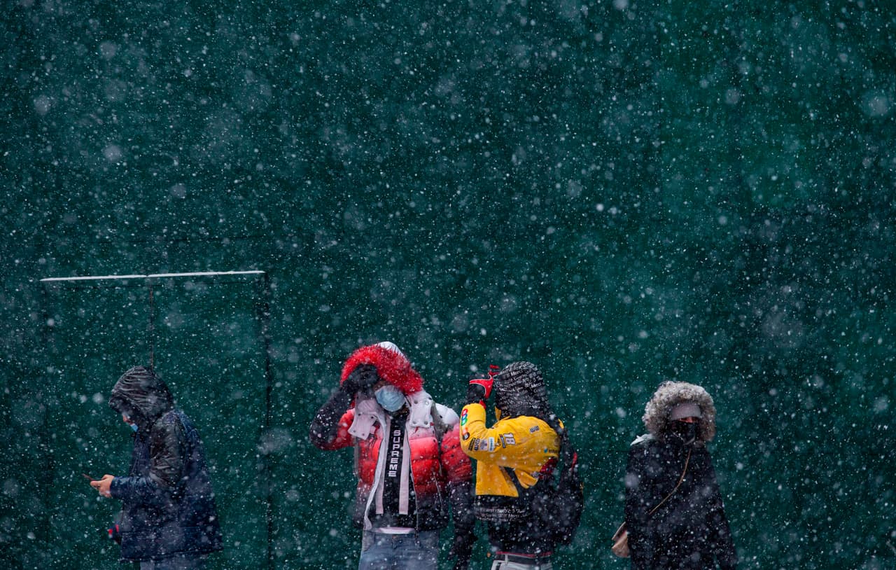 La nieve cae mientras la gente camina por Times Square