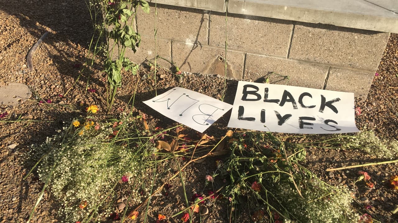 En un lado de la vía se observa un pequeño altar con flores, ramas y letreros.
